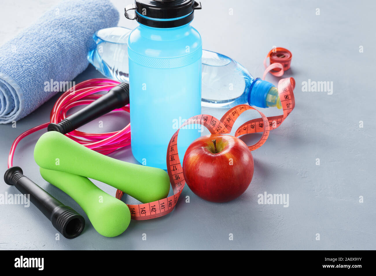 Satz von verschiedenen Fitnessgeräte - Kurzhanteln, Wasserflasche, Springseil und Handtuch. Outfit für Fitnessraum oder zu Hause. Gesunder Lebensstil Konzept. Stockfoto