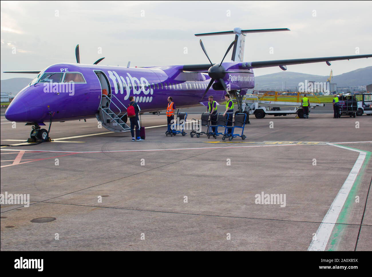 21. September 2019 eine FlyBe Dash 8 Verkehrsflugzeug mit Gepäck und Passagiere Handler auf dem Vorfeld des George Best City Airport in Belfast, Nordirland Stockfoto