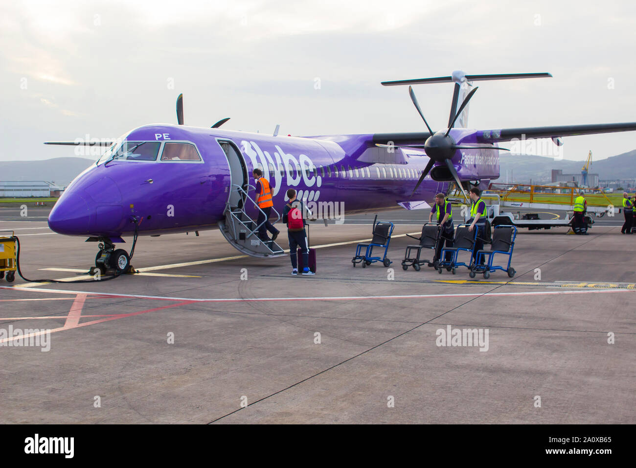 21. September 2019 eine FlyBe Dash 8 Verkehrsflugzeug mit Gepäck und Passagiere Handler auf dem Vorfeld des George Best City Airport in Belfast, Nordirland Stockfoto