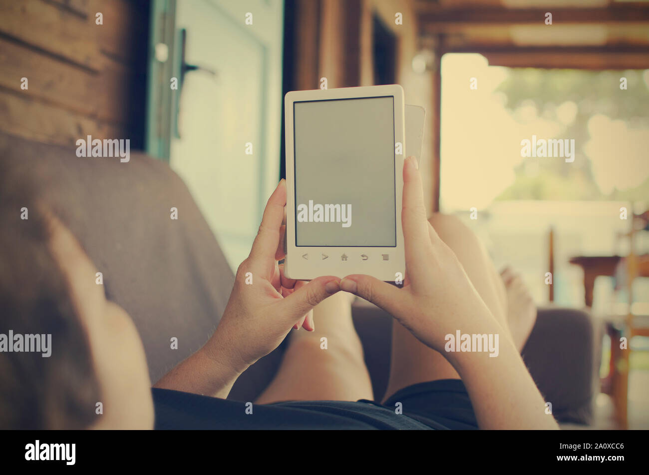 Kaukasische Frau lesen ebook auf der Couch. Kopieren Sie Platz. Selektiver Fokus auf Hände und Buch. Stockfoto