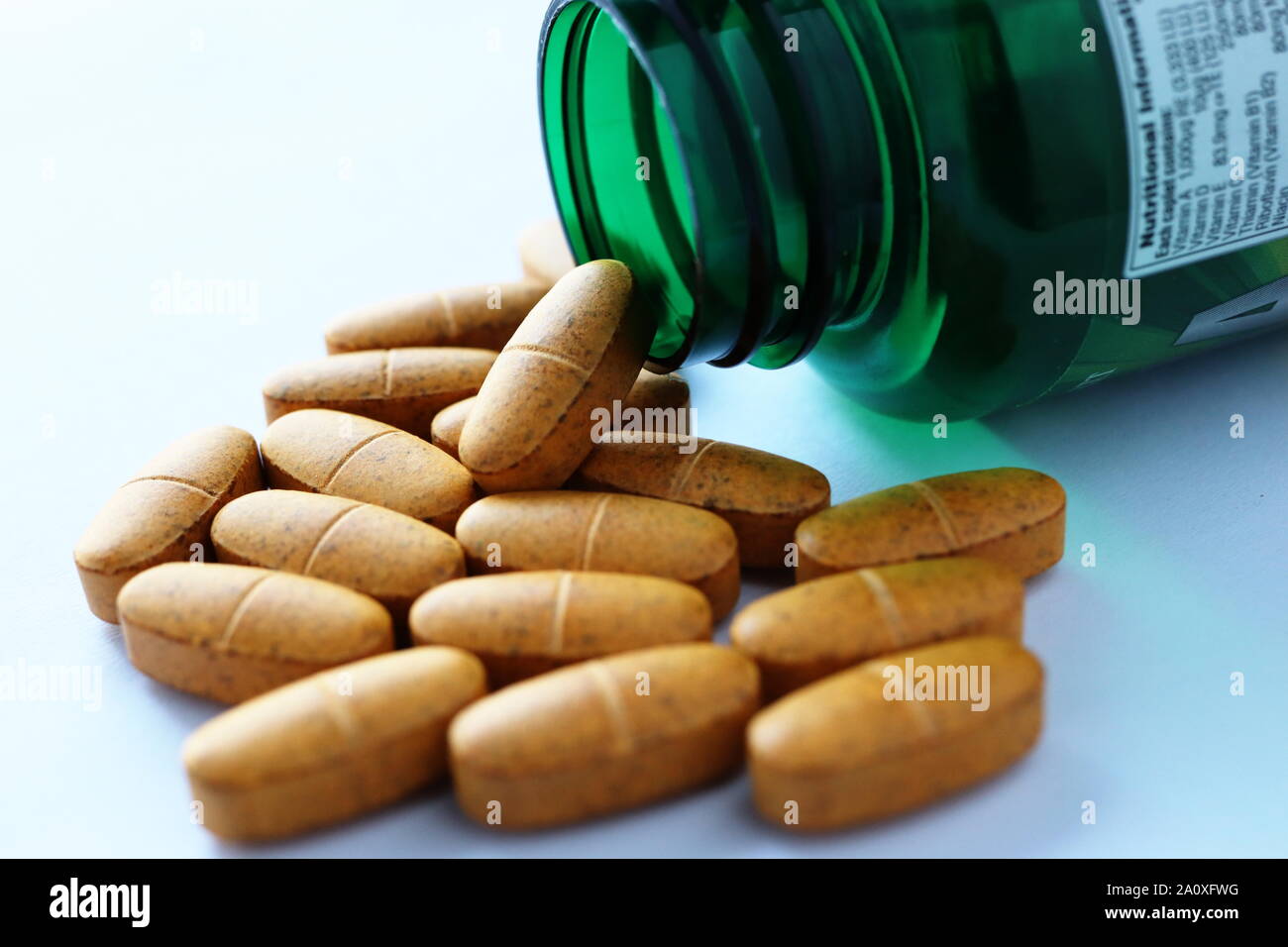 Multivitamin Tabletten und grünen Container, Flasche mit Etikett mit Nährwertangaben, Inhalt, und der empfohlenen täglichen Aufnahmemengen. Stockfoto