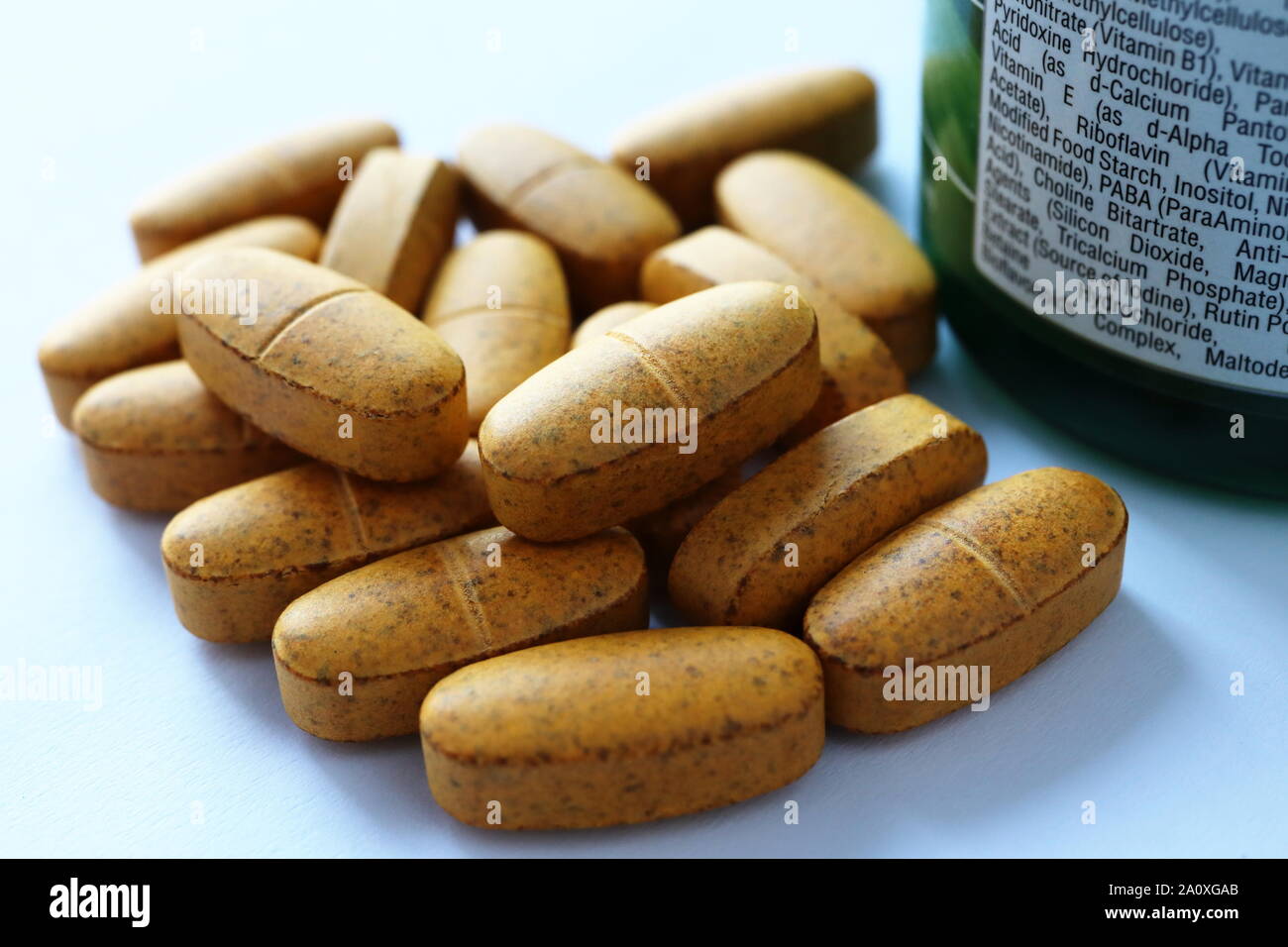 Multivitamin Tabletten und grünen Container, Flasche mit Etikett mit Nährwertangaben, Inhalt, und der empfohlenen täglichen Aufnahmemengen. Stockfoto