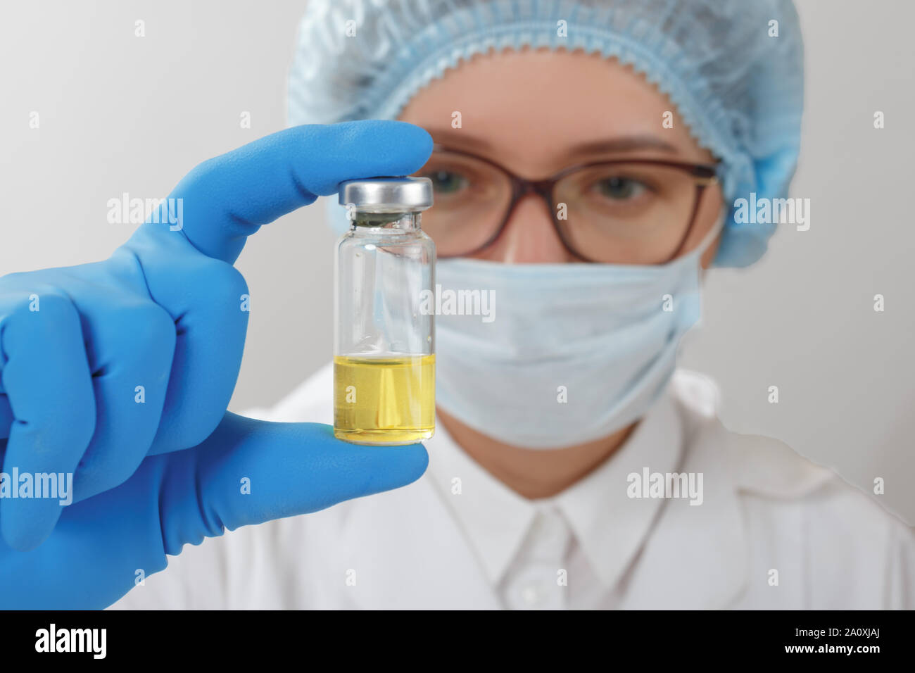 Wissenschaftlerin in Schutzhandschuhe und Schutzbrille in ein Reagenzglas in einem Labor. Stockfoto