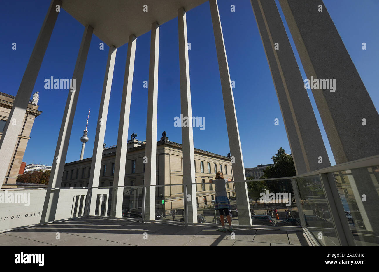 22. September 2019, Berlin: Ein Junge steht bei sommerlichen Temperaturen auf ein Geländer zwischen hohen Säulen des James Simon Galerie. Der Fernsehturm auf dem Horizont vor blauem Himmel gesehen werden. Foto: Jörg Carstensen/dpa Stockfoto