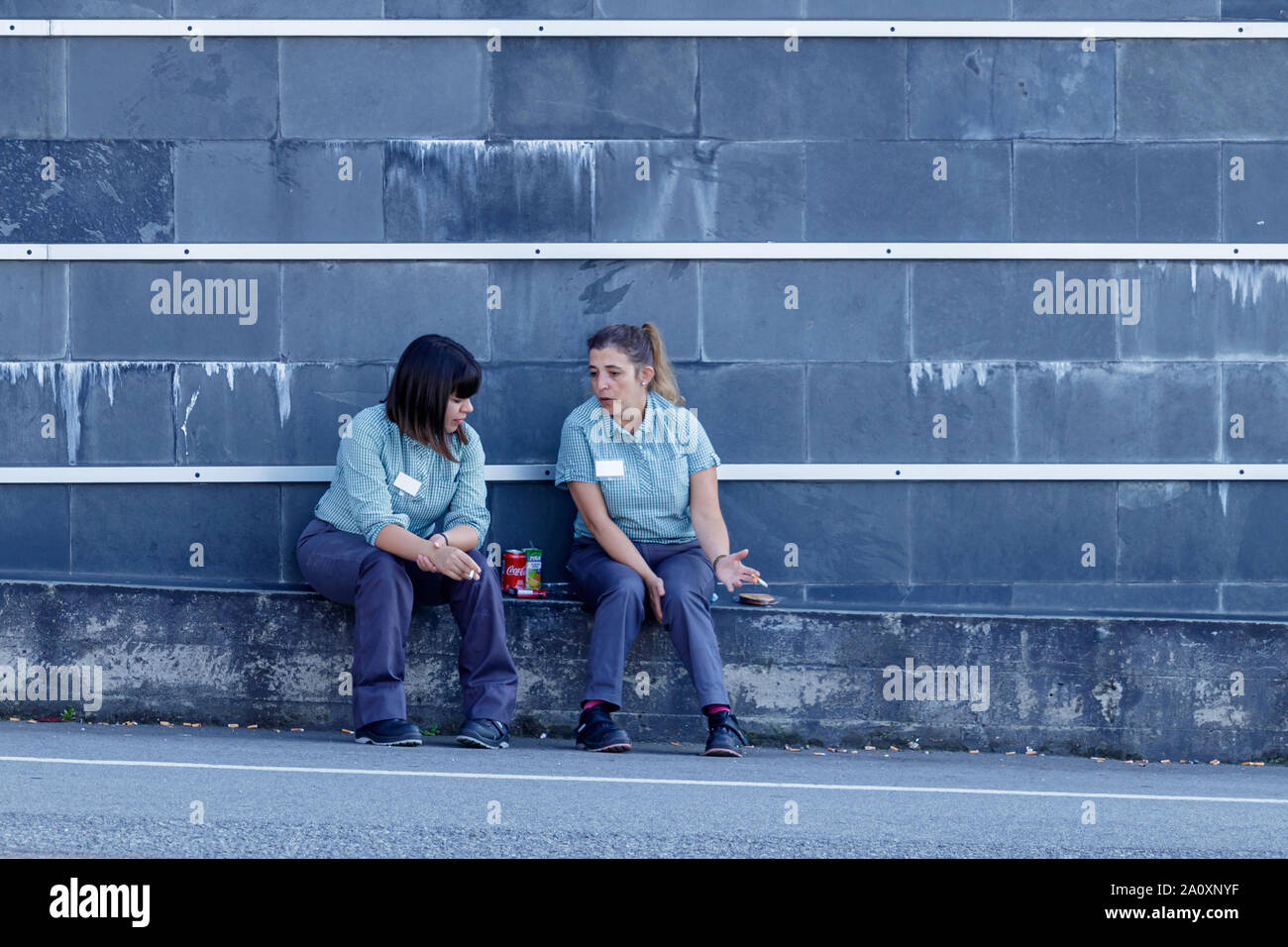 Coruna/Spanien - 22. August 2019: Zwei Frauen auf eine Zigarettenpause außerhalb einen Supermarkt in Coruna Spanien Stockfoto