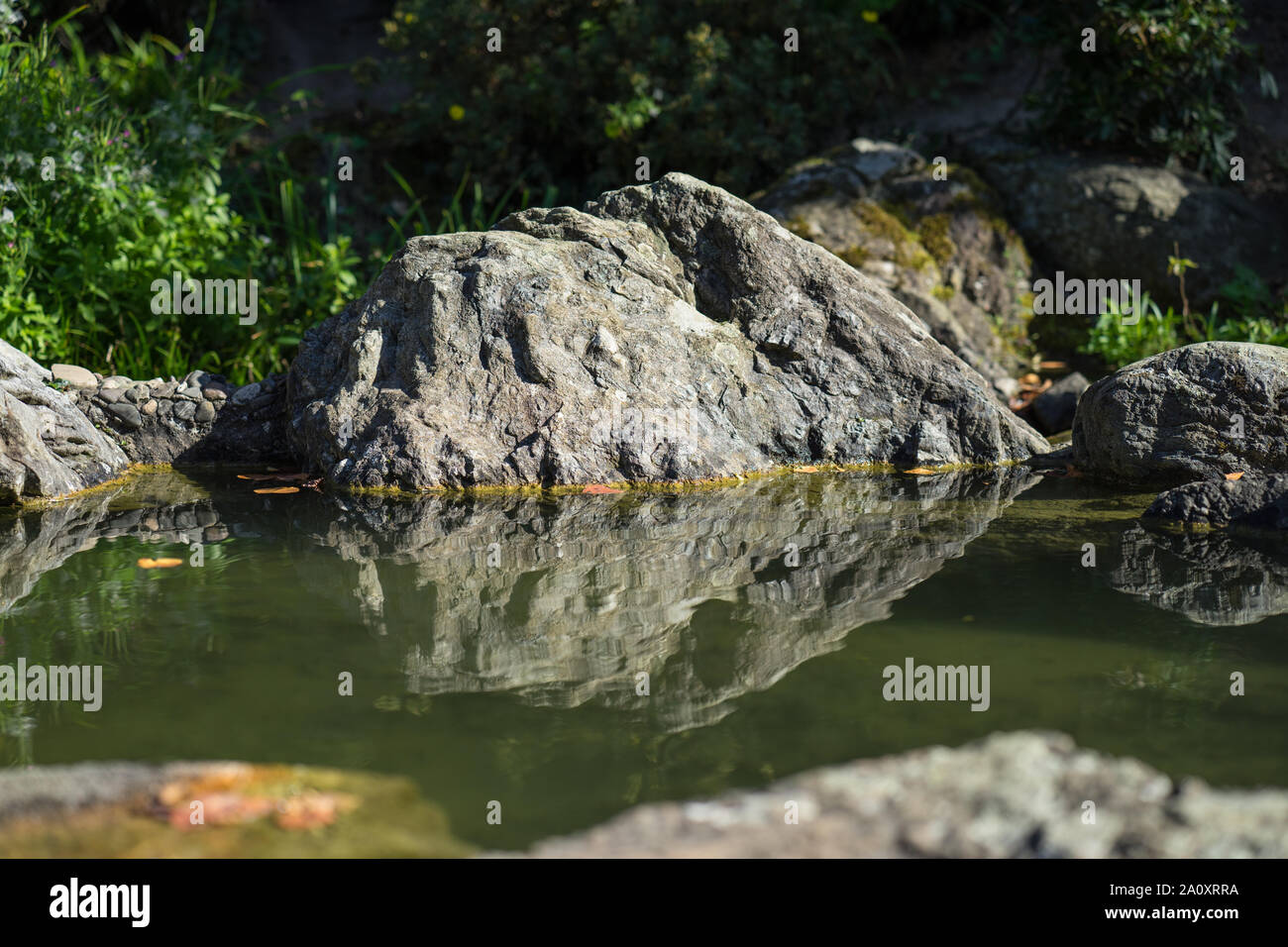 Felsen in einer ruhigen Bach im Wasser spiegelt. Stockfoto