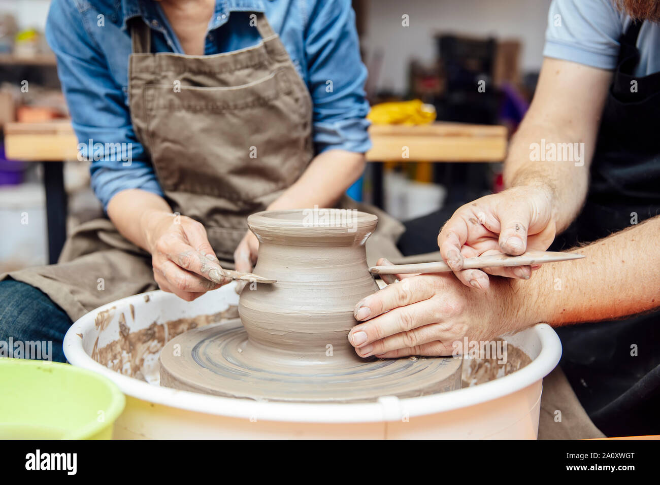 Ältere Frau spinnen Ton auf einem Rad mit Hilfe eines Lehrers an Keramik Klasse Stockfoto