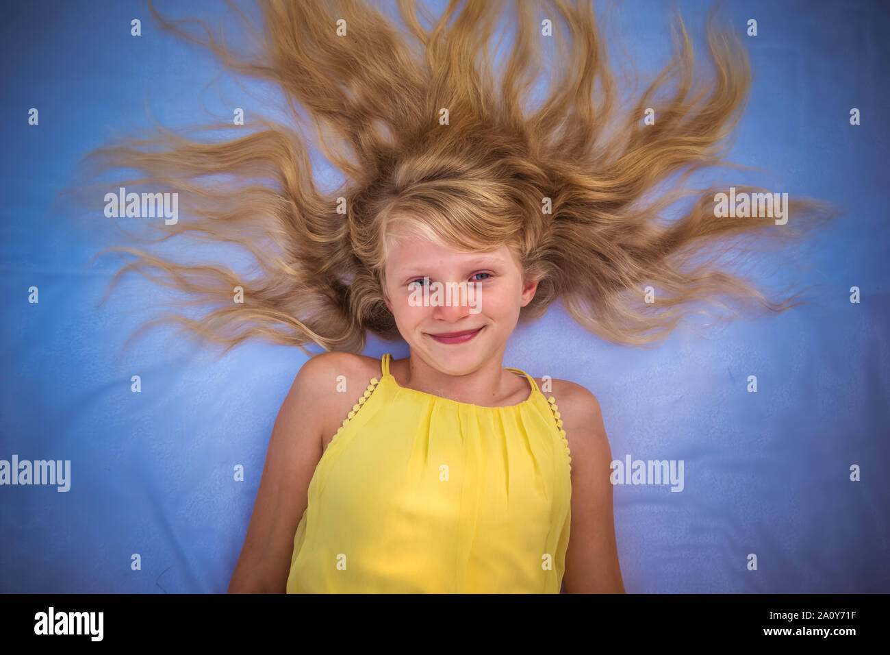 Close up Portrait von entzückenden kleinen Mädchen liegt mit unordentlichen lange blonde Haare Stockfoto