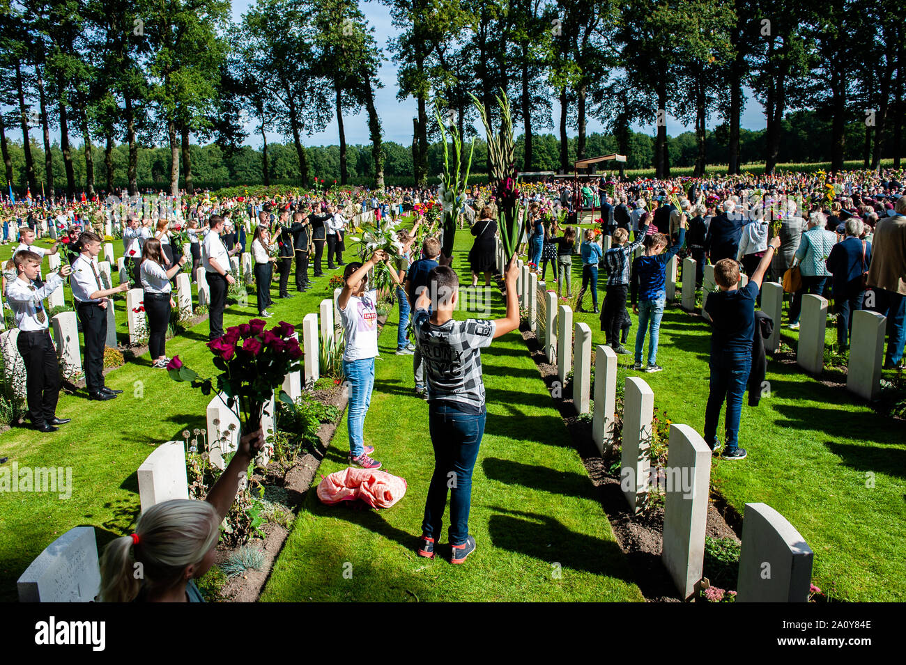 Kinder steigen Blumen in den Himmel während des Gedenkens. An der Arnhem Oosterbeek Soldatenfriedhof, mehr als 1.750 alliierte Soldaten beerdigt wurden. Im Rahmen der Gedenkfeiern zum 75. Jahrestag der Operation Market Garden, eine Trauerfeier in der Anwesenheit von Veteranen gehalten wurde, ihren Angehörigen und Tausende von Menschen. War ein weißer Stein Bogen an jedem Grab gelegt. Auf dem Feld der Ehre ist ein 'Kreuz der Opferung" aus Portland Stein, auf dem ein Bronzenes Schwert befestigt ist. Stockfoto