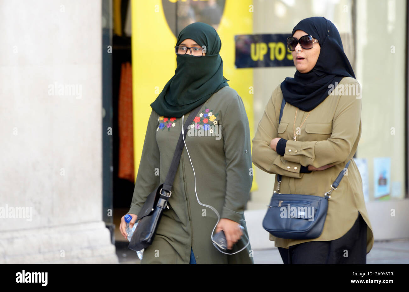 Zwei muslimische Frauen, eine in Niqab, Hijab, Geschäften vorbei gehen. Stockfoto