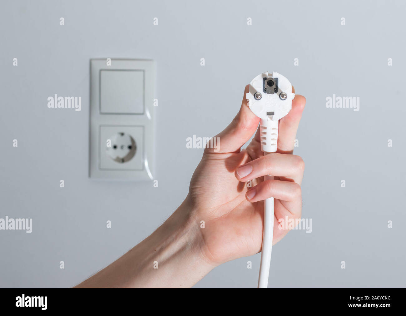 Den weißen Stecker mit Kabel in Männer hand, bereit, zu verbinden. Energiekonzept. Stockfoto