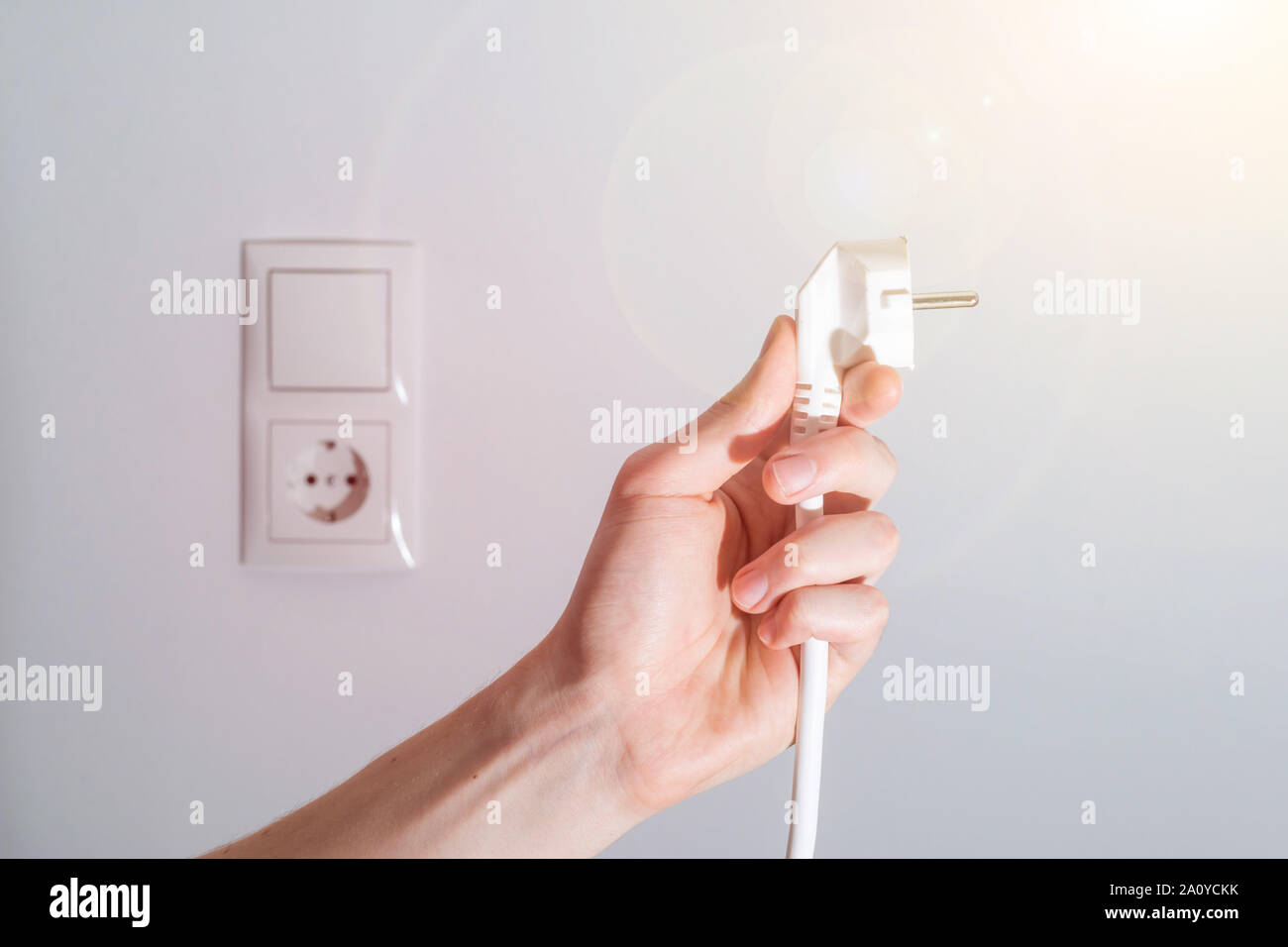 Den weißen Stecker mit Kabel in Männer hand, bereit, zu verbinden. Energiekonzept. Stockfoto