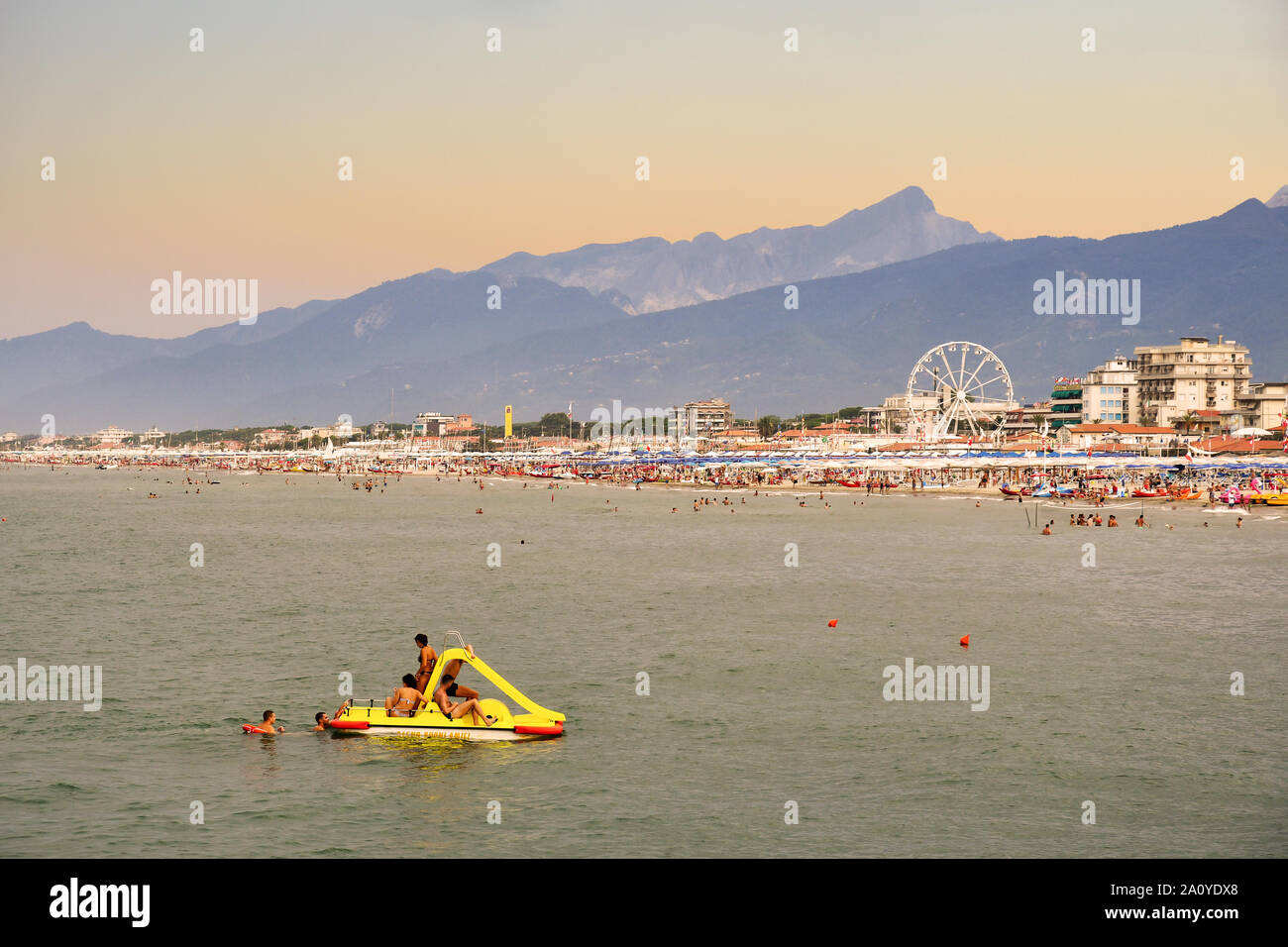 Ansicht der Toskana Küste mit einer Gruppe von Freunden Spaß auf ein Tretboot und das Stadtbild von Lido di Camaiore bei Sonnenuntergang im Sommer, Versilia, Italien Stockfoto