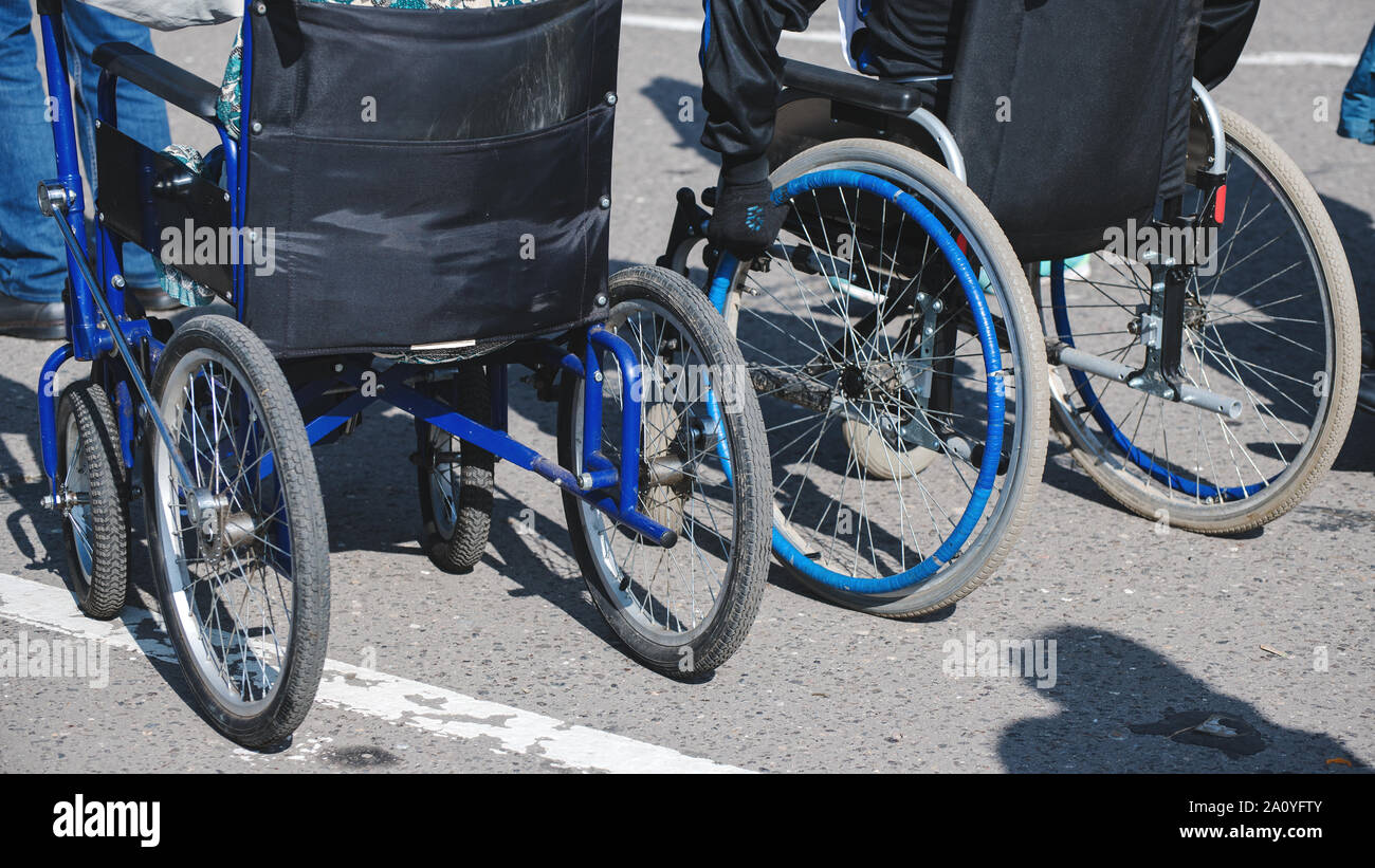 Rollstuhl Räder closeup auf Asphalt. Das Konzept der sozialen Gleichheit, Schutz und Unterstützung der Menschen mit Behinderungen Stockfoto