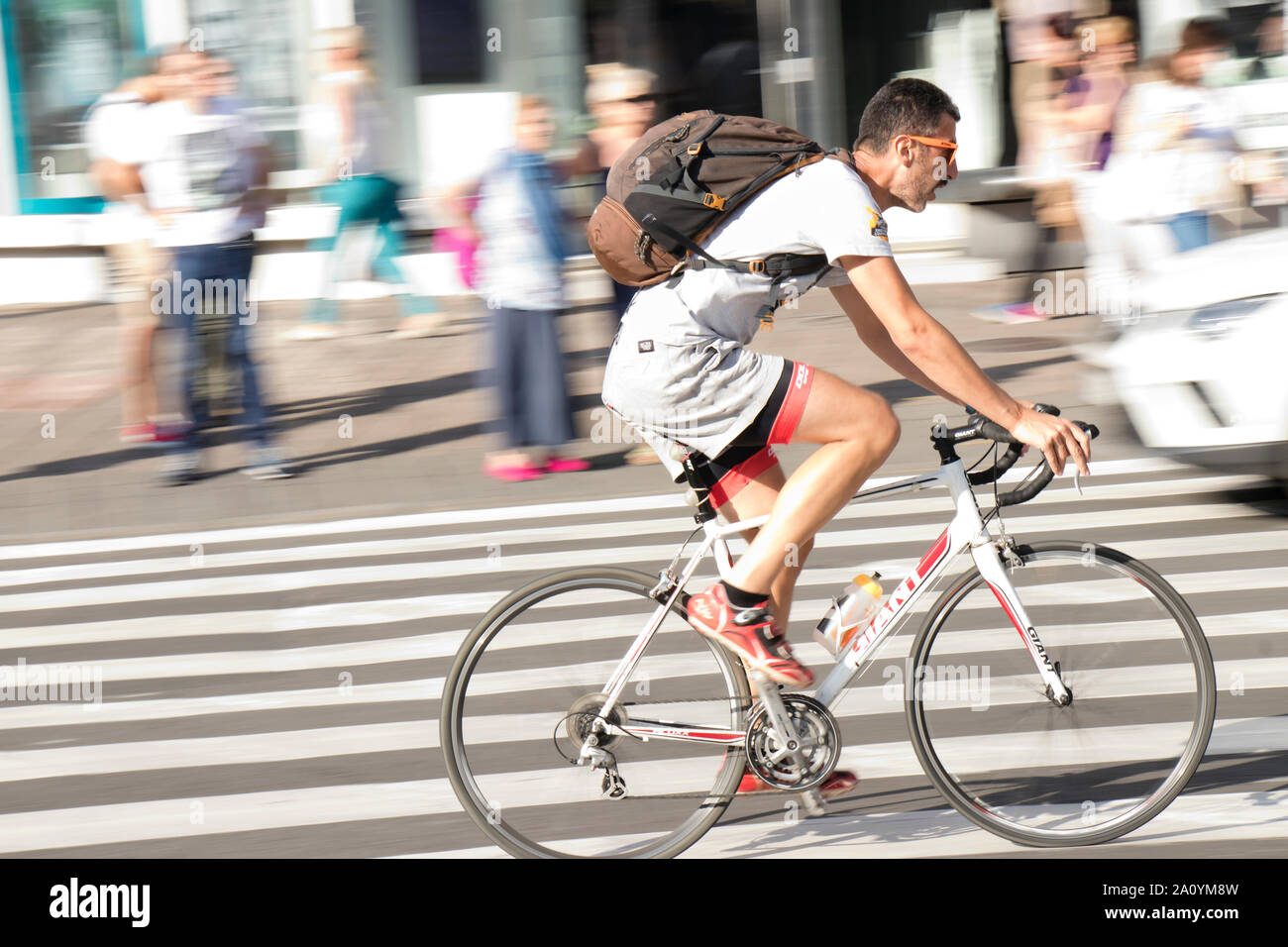 Belgrad, Serbien - 17. September 2019: Ein reifer Mann in Shorts und T-Shirt mit einem Rucksack auf einem weißen Fahrrad in der Stadt Straße Verkehr Stockfoto