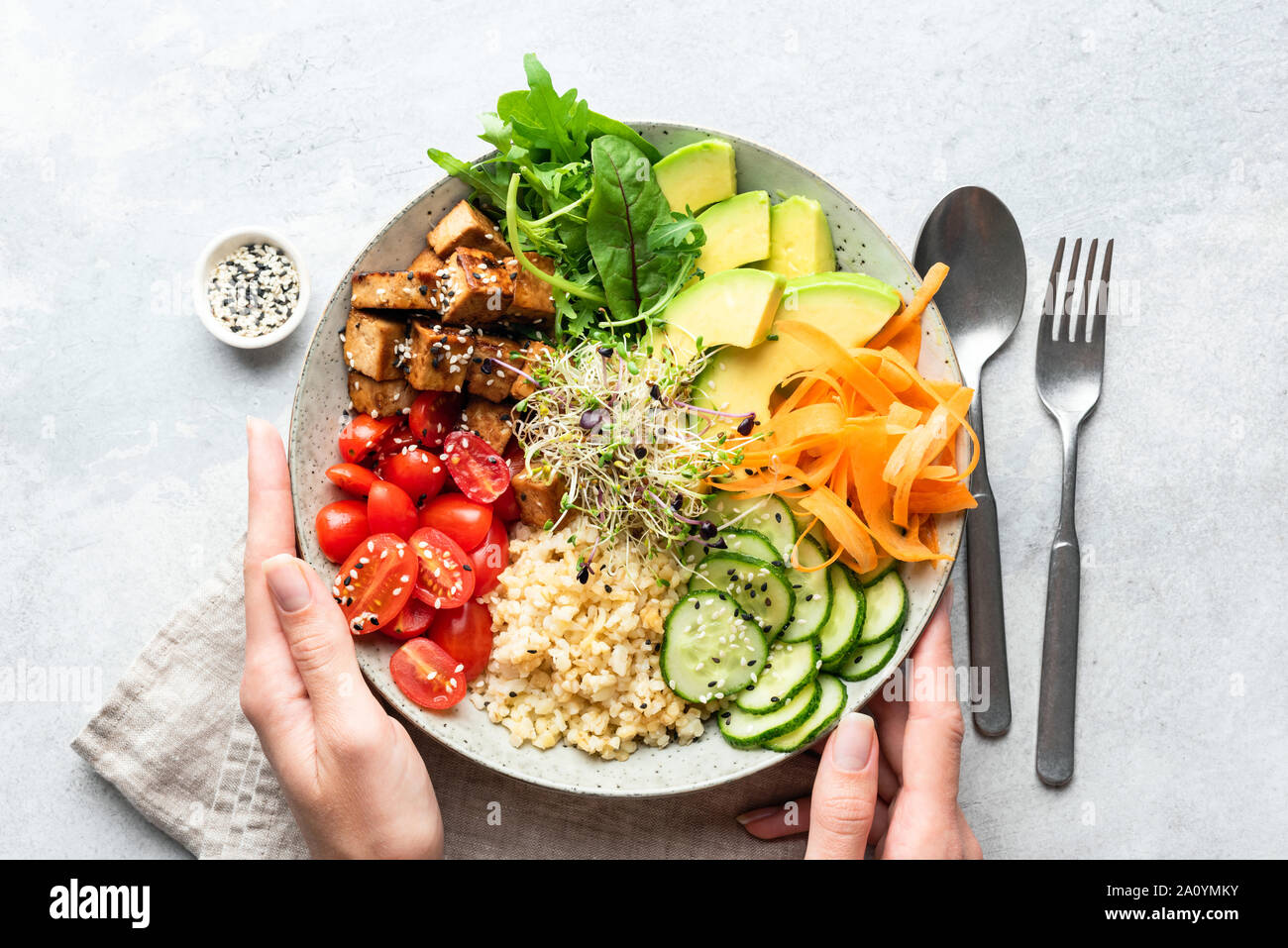 Buddha Schüssel Salat in weiblichen Händen, ausgewogene Mahlzeit. Hell Grau konkreten Hintergrund, Ansicht von oben. Gewichtsverlust, Diäten Konzept Stockfoto