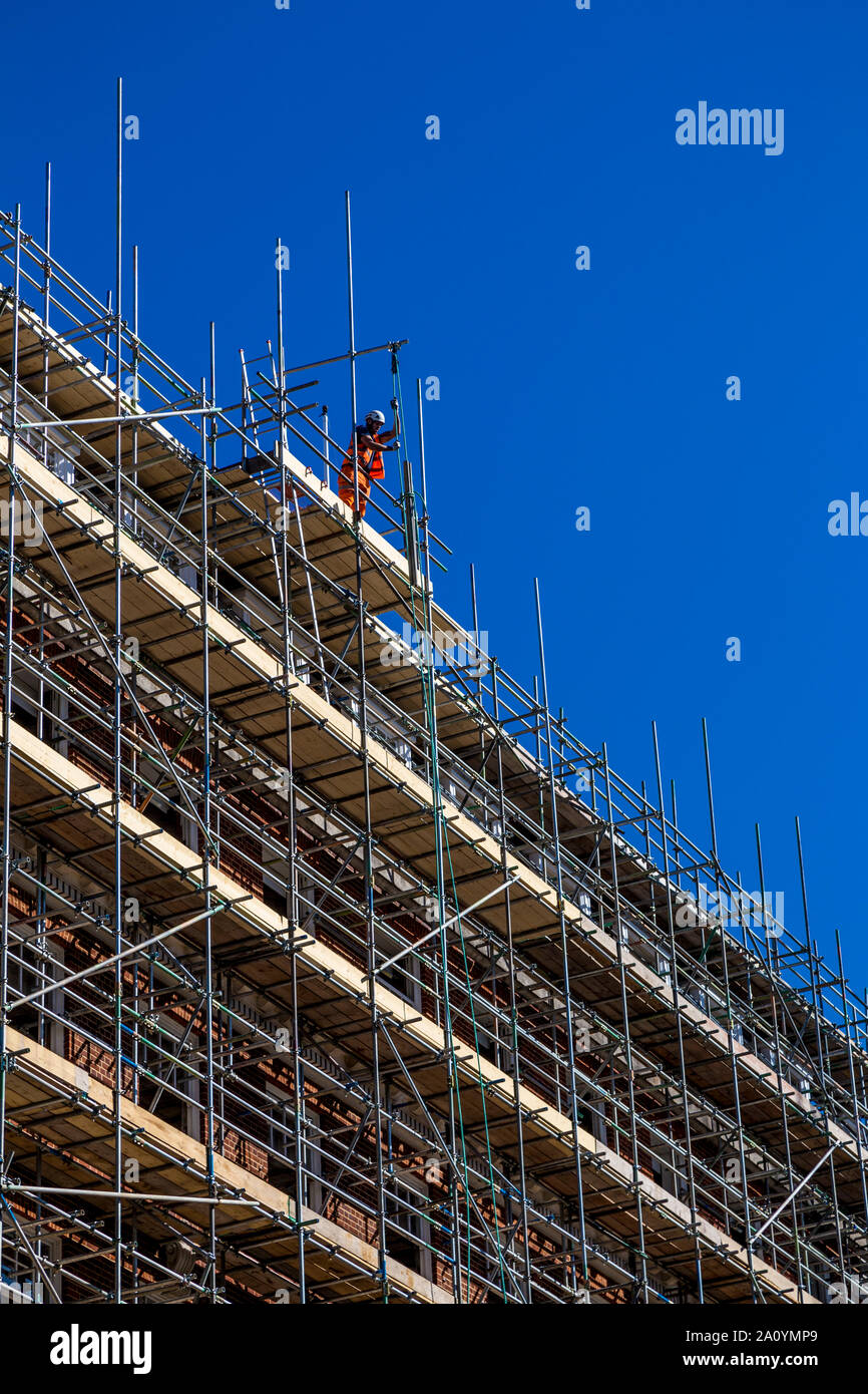 Bauarbeiter auf Gerüsten,, indem sie Materialien auf der Spitze des Gebäudes Stockfoto