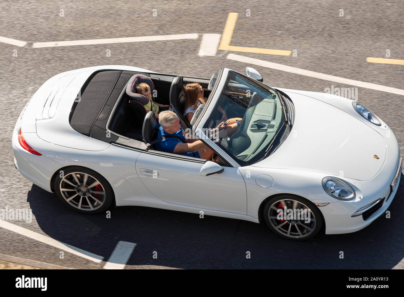Porsche offene Sportwagen mit Kind hinten im Kindersitz auf Western Esplanade, Southend On Sea, Essex, Großbritannien. Roadster Fahrzeug mit begrenztem Raum Stockfoto