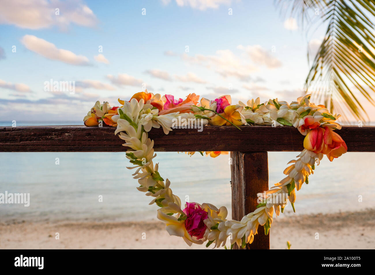 Eine schöne Lei von Blumen steht auf dem Geländer einer Holzterrasse mit Blick auf eine Lagune in Französisch Polynesien im Südpazifik Stockfoto