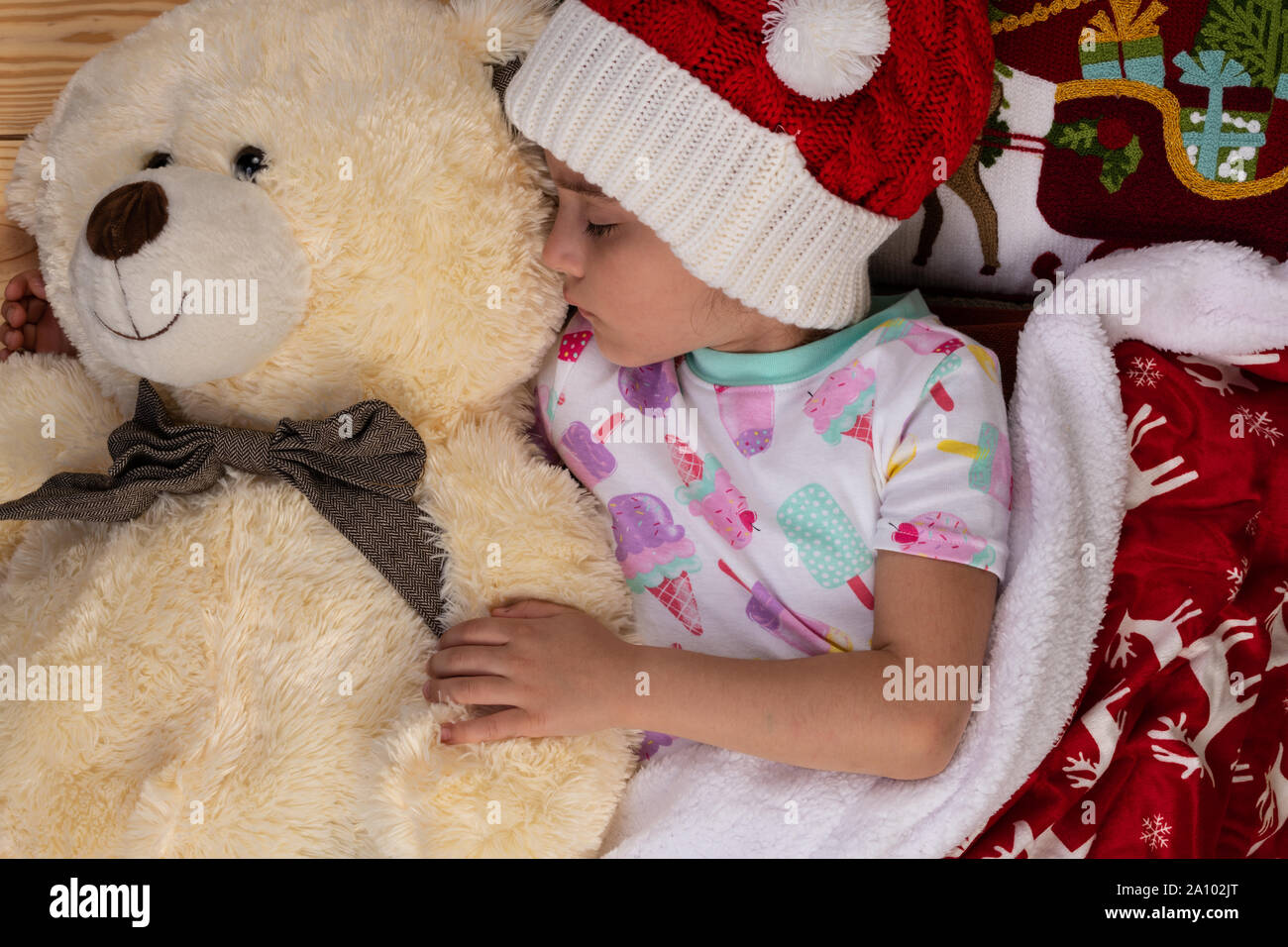 Schlafende Mädchen zu Hause an Weihnachten mit großen Teddybär Plüsch Spielzeug. Neues Jahr Winterurlaub Konzept. Stockfoto