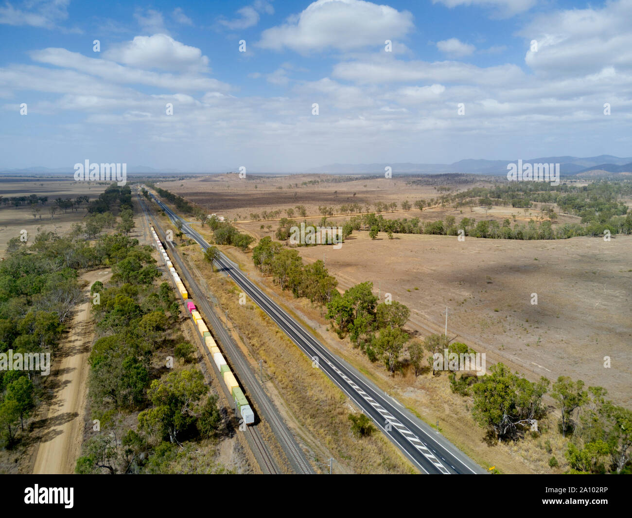 Antenne von gemischten Güterzug durch einen Boom gesteuert Bahnübergang Position entlang der Seite des Bruce Highway Queensland Australien vorbei Stockfoto
