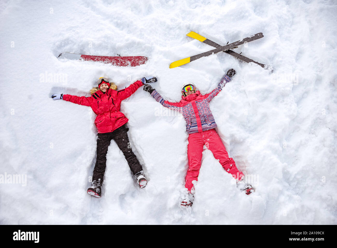 Skifahrer und Snowboarder liegen auf Schnee mit Ski und Snowboard und Spaß haben. Luftbild Stockfoto