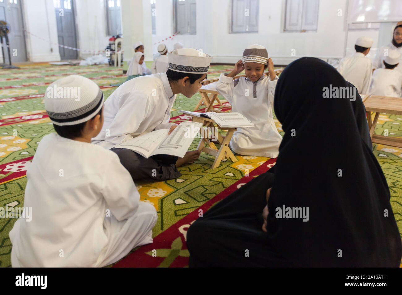 Ein jüngeres Malay Lehrer unterrichten einer Gruppe von Kindern im Inneren Masjid Moschee, Singapur Stockfoto