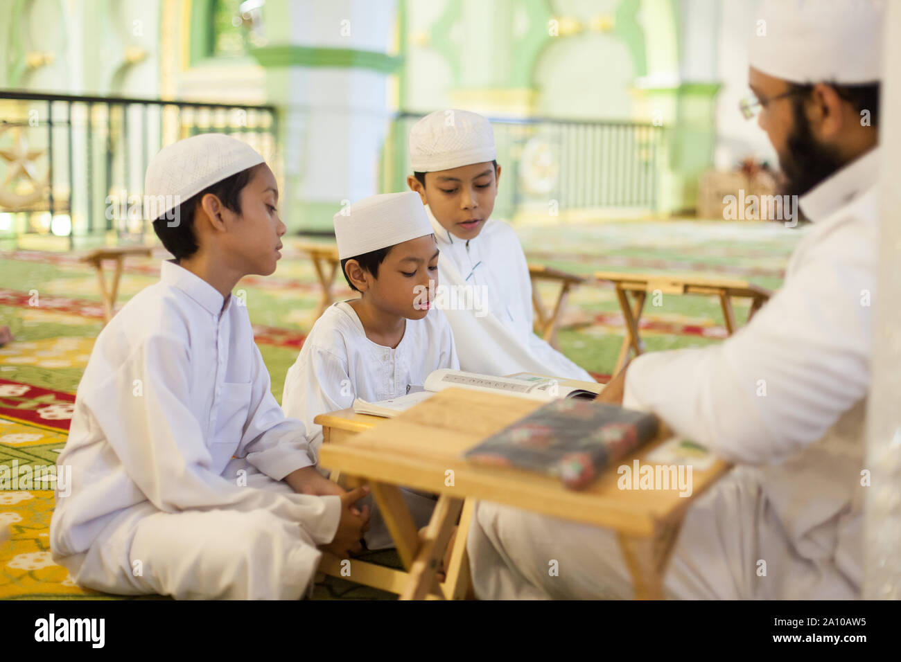 Ein erwachsener Religion Lehrer unterrichten von Kindern studieren im Inneren Masjid Moschee, Singapur Stockfoto