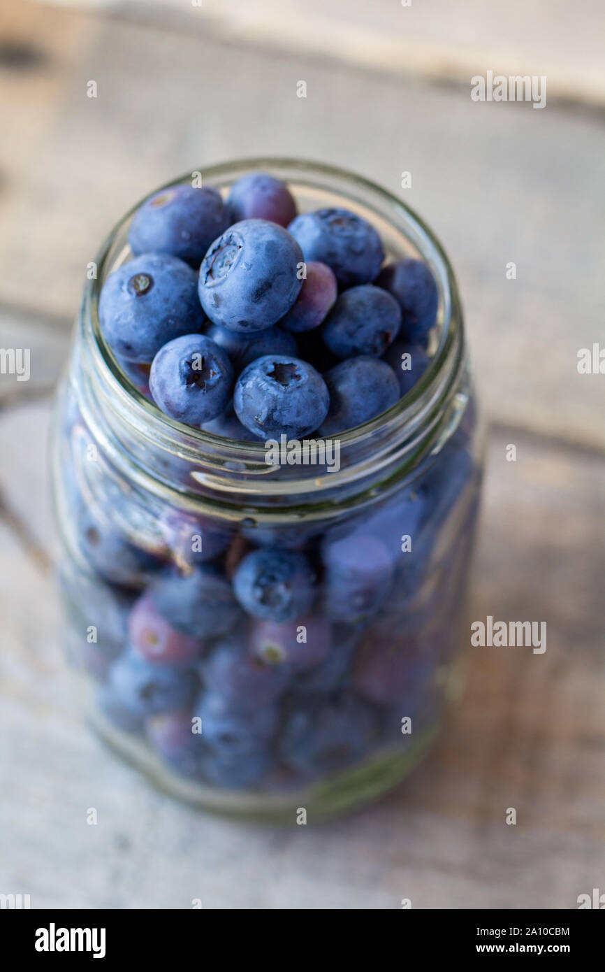 Blaubeeren in einem Glas auf einem Holztisch Stockfoto
