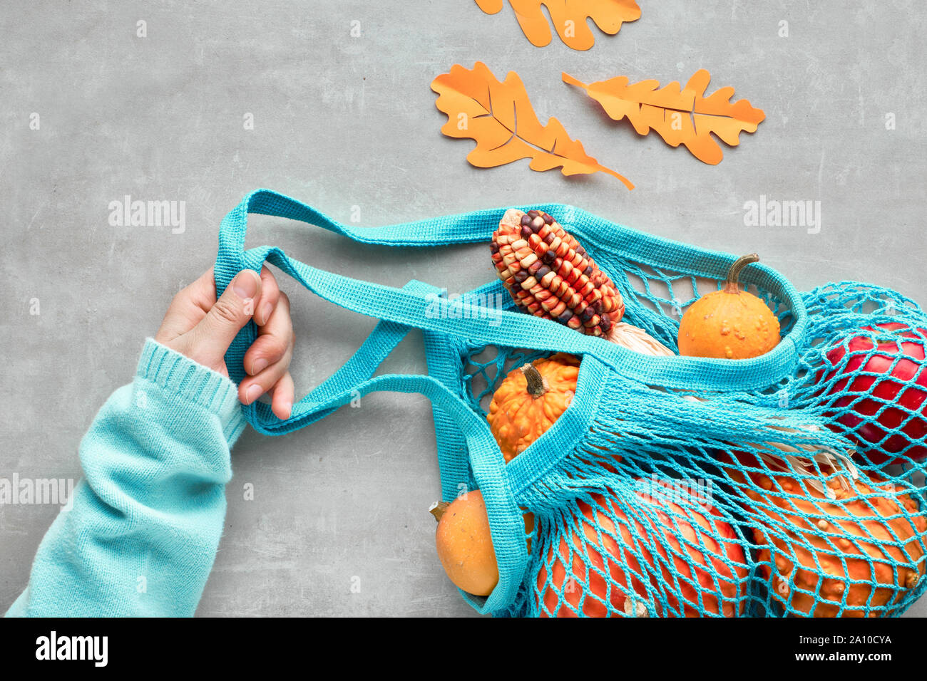 Herbst flach mit Türkis string Tasche mit orange Kürbisse, top vie am grauen Stein Hintergrund Stockfoto