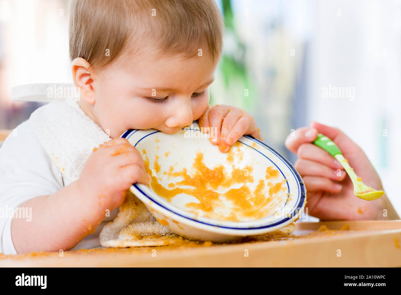 Sweet messy baby boy beißen Teller nach dem Essen das Essen. Stockfoto