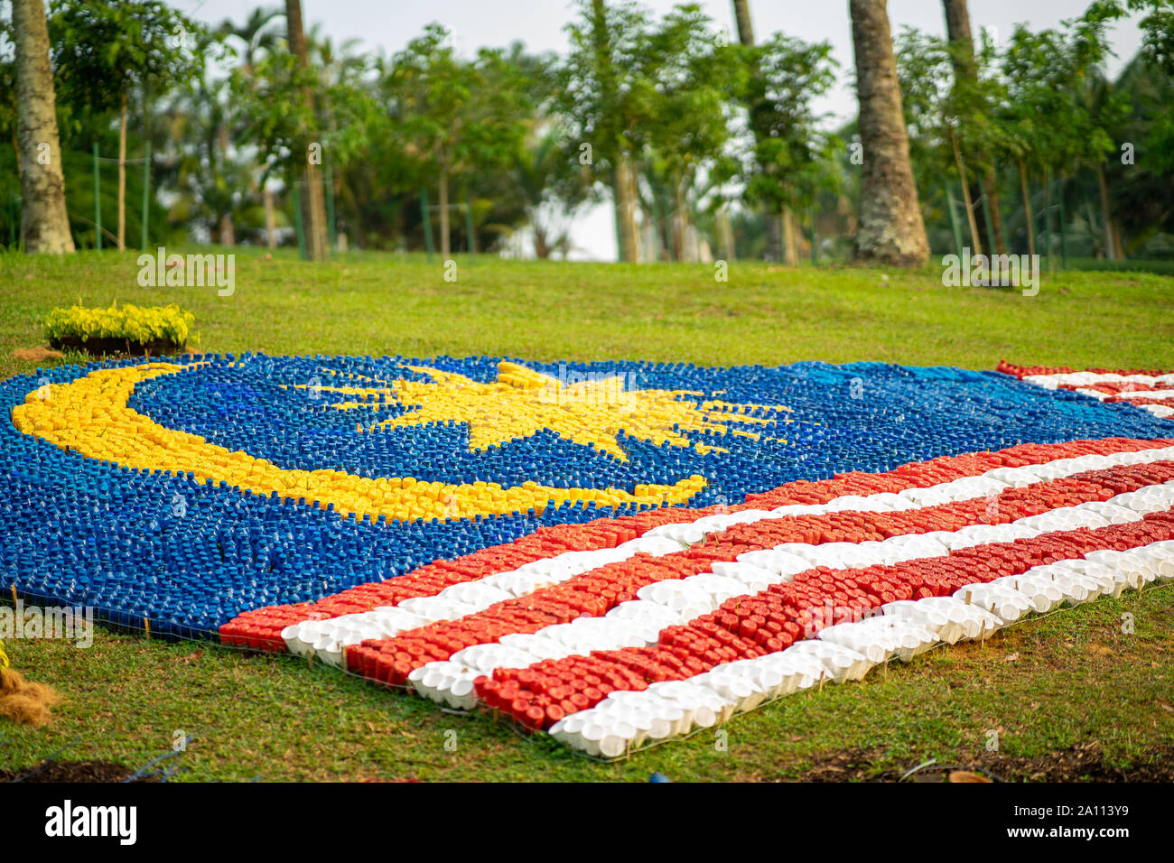 Malaysische Flaggen aus recycelten Flaschen auf dem Boden liegend im Garten gemacht. Stockfoto