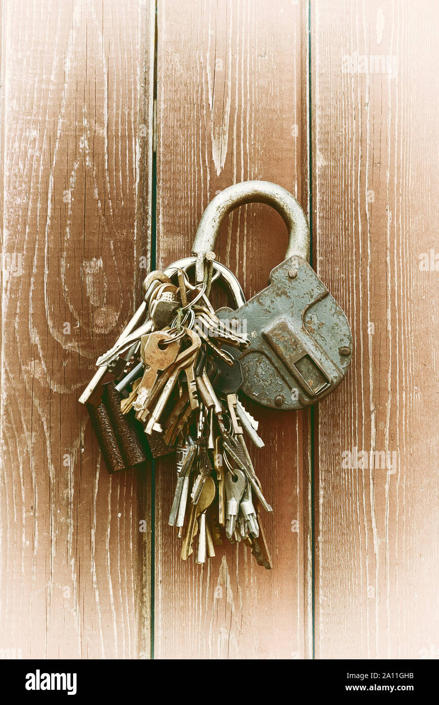 Ein Haufen alter Schlüssel und zwei Schlösser hängen sie an einen Nagel in eine Wand gefahren. Jahrgang. Stockfoto
