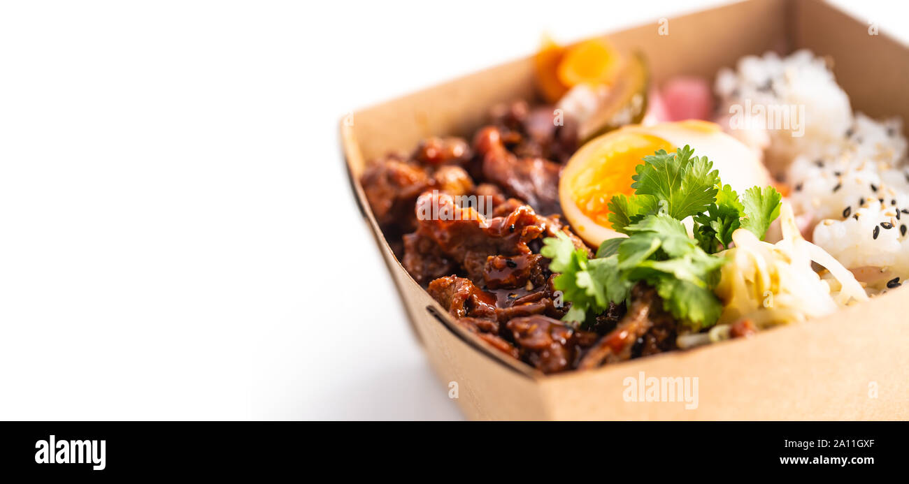 Japanische asiatische Mahlzeit in einer Box von Recyclingpapier auf weißem Hintergrund. Stockfoto