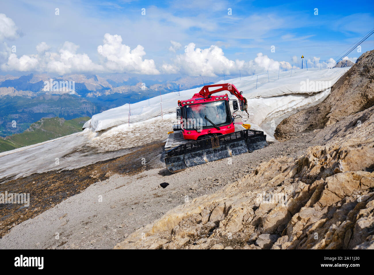 Marmolada Gletscher, Italien - 28. August 2019: PistenBully Pistenfahrzeug Maschine Parken neben dem restlichen Schnee Patch, mit einer Sonne schützen Wh abgedeckt Stockfoto