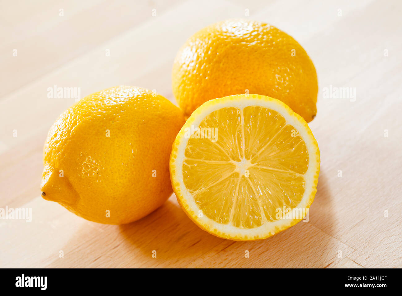 Zitronen auf einer hölzernen Oberfläche, ganze und halbe Stockfoto