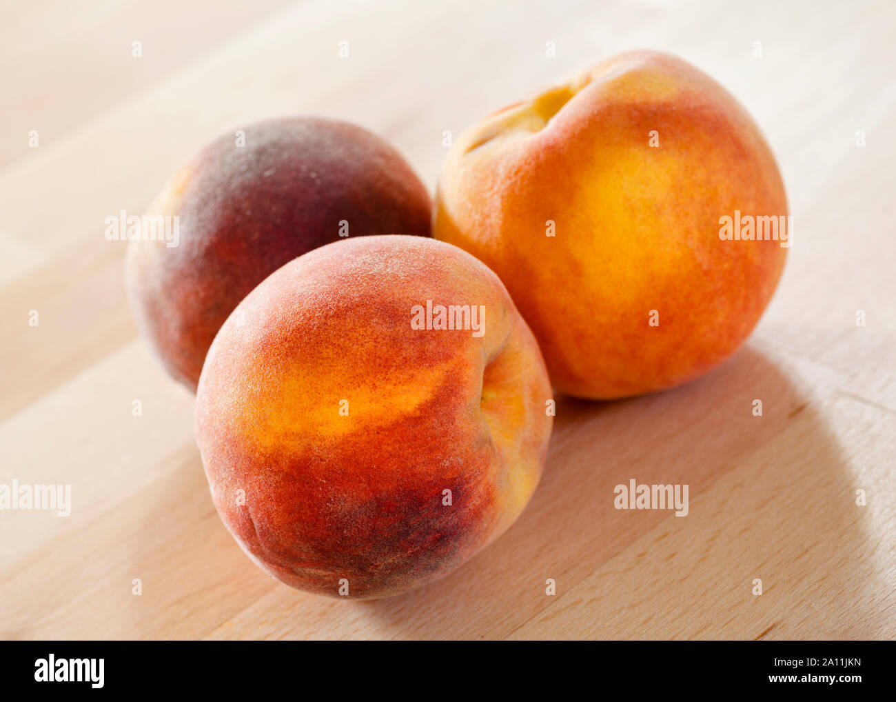 Drei Pfirsiche auf einem hölzernen Oberfläche Stockfoto