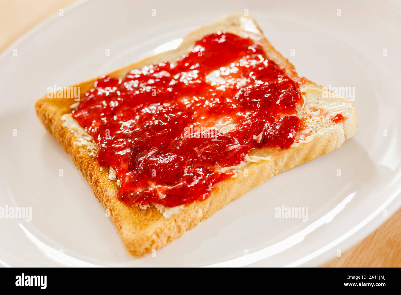 Toast und Erdbeermarmelade auf einer weißen Platte Stockfoto