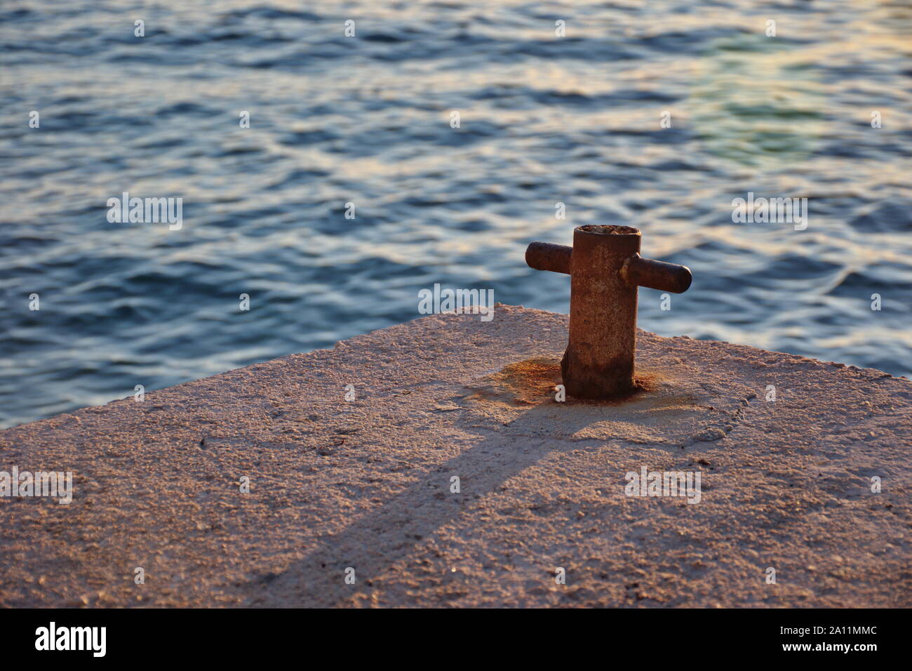 Closup konkreter Dock mit Metall Keil gegen die blauen Meer im Sonnenuntergang Stockfoto