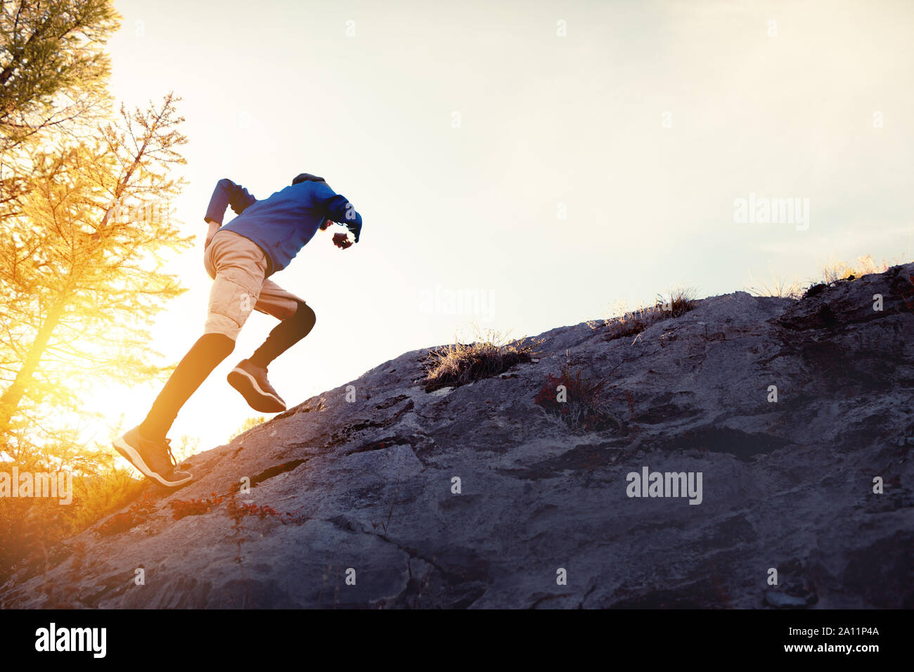 Der Mensch läuft bergauf von Big Rock gegen Sonnenuntergang Himmel Stockfoto