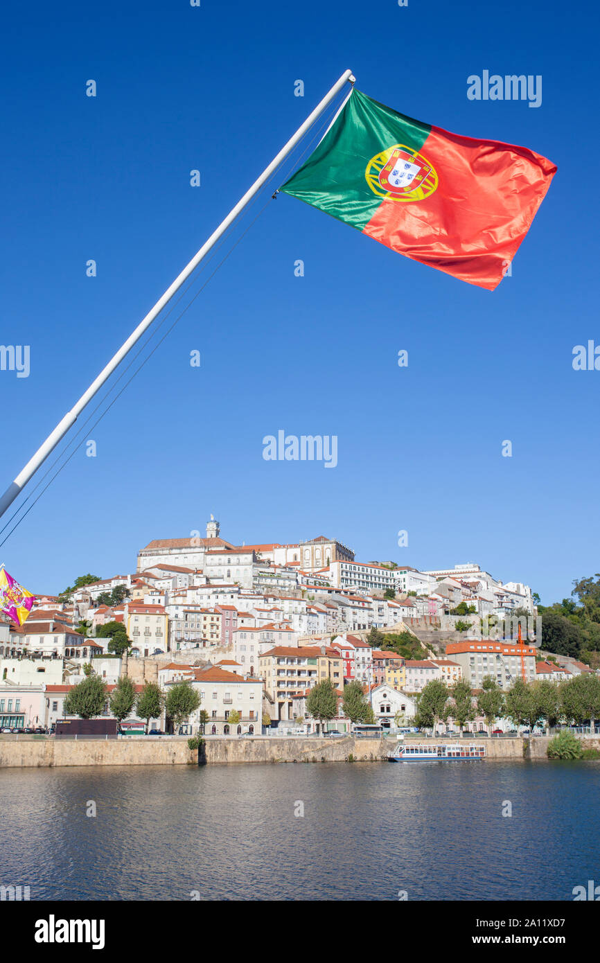 Blick auf die Altstadt von Coimbra aus Santa Clara Brücke mit Portugal Flagge das Weben in den blauen Himmel. Coimbra ist eine wunderschöne historische Stadt mit vielen touristischen sp Stockfoto