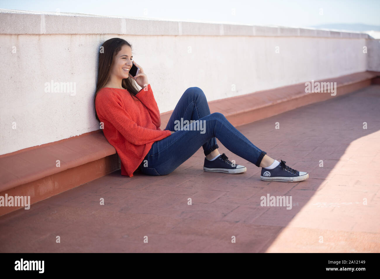 Chica adolescente sentada hablando por teléfono en La Azotea Stockfoto