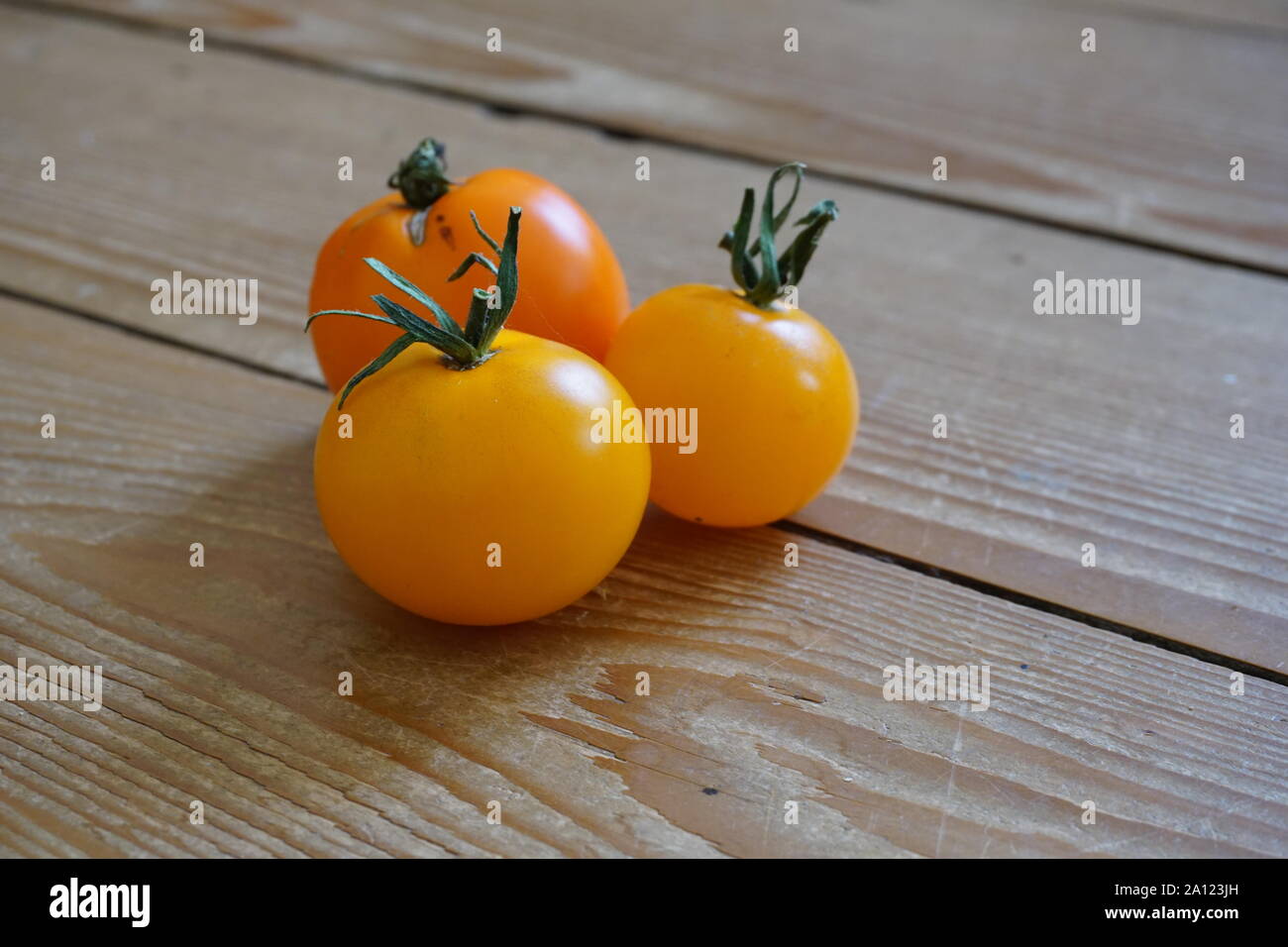 Gruppe von kleinen gelben Kirschtomaten auf einem rustikalen Holztisch Stockfoto