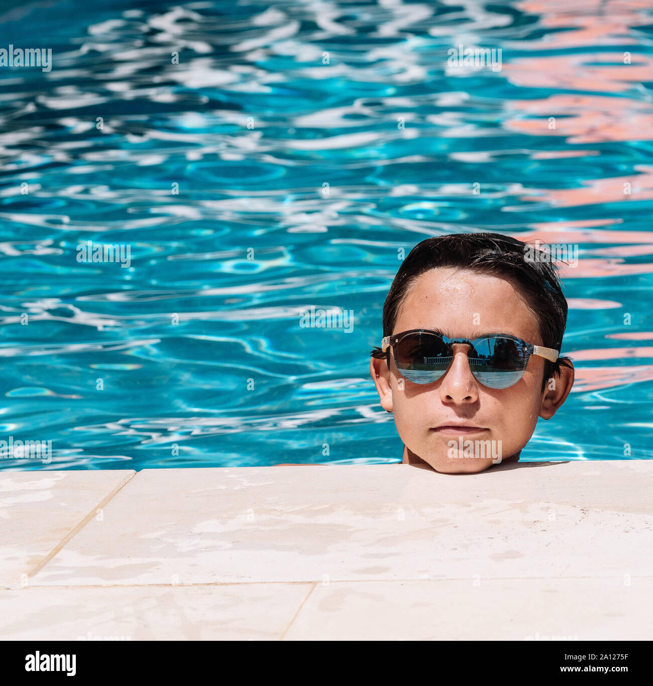 Pre-teens Pose mit Sonnenbrille durch die Kante des Pool Stockfoto