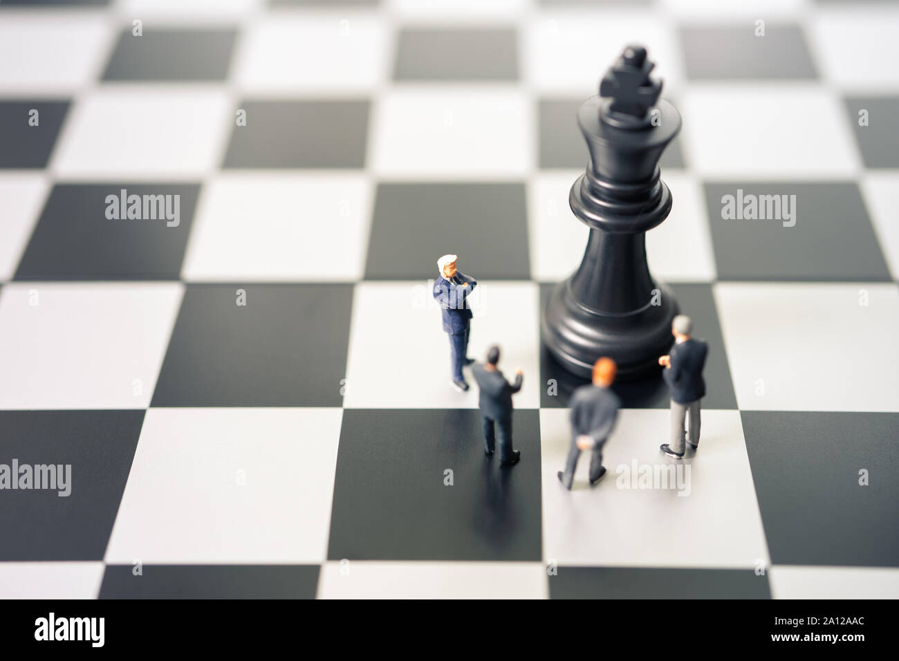 Miniatur Menschen Unternehmer stehend auf einem Schachbrett mit einer Schachfigur auf der Rückseite der Aushandlung im Geschäft. Als Hintergrund Geschäftskonzept und Strat Stockfoto