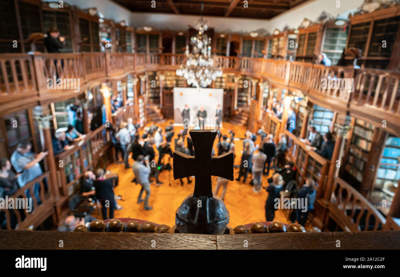 Fulda, Deutschland. 23 Sep, 2019. Ein Holzkreuz auf dem Geländer der Bibliothek über der Halle angebracht, während im Hintergrund Kardinal Reinhard Marx, Vorsitzender der Deutschen Bischofskonferenz, an die Vertreter der Medien auf einer Pressekonferenz spricht vor Beginn der Herbst Vollversammlung. Die geplante Reform innerhalb der Katholischen Kirche ist das Hauptthema der diesjährigen Tagung der Deutschen Bischöfe. Foto: Frank Rumpenhorst/dpa/Alamy leben Nachrichten Stockfoto