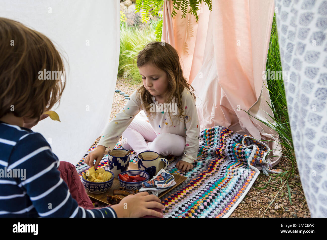 Jungen und Mädchen spielen im Freien improvisierten Zelt Stockfoto