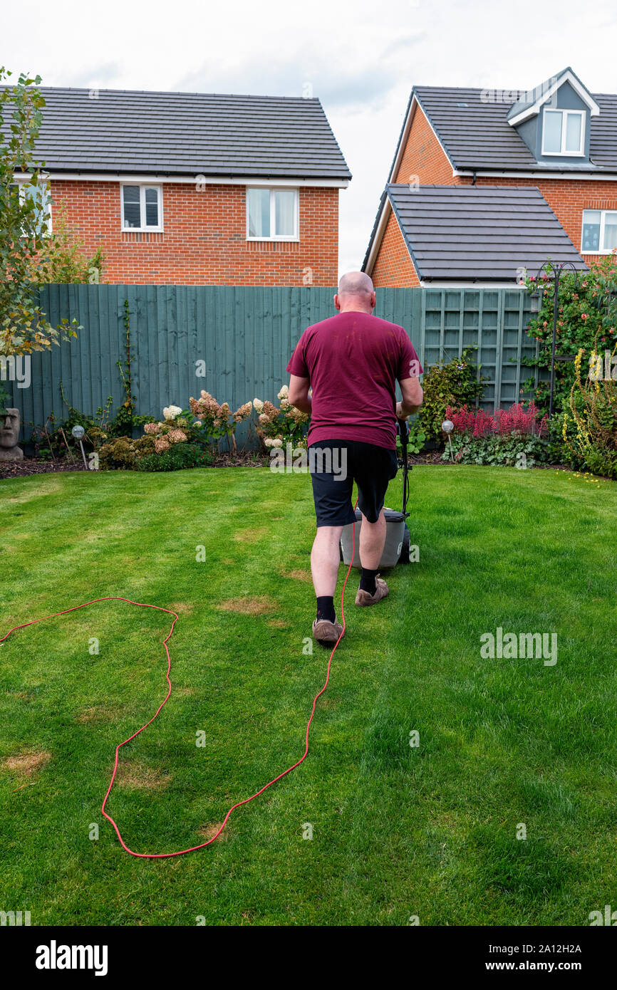 Man mäht seinen Rasen mit einem Speer und Jackson elektrische Rasenmäher (zurück in die Kamera) Stockfoto