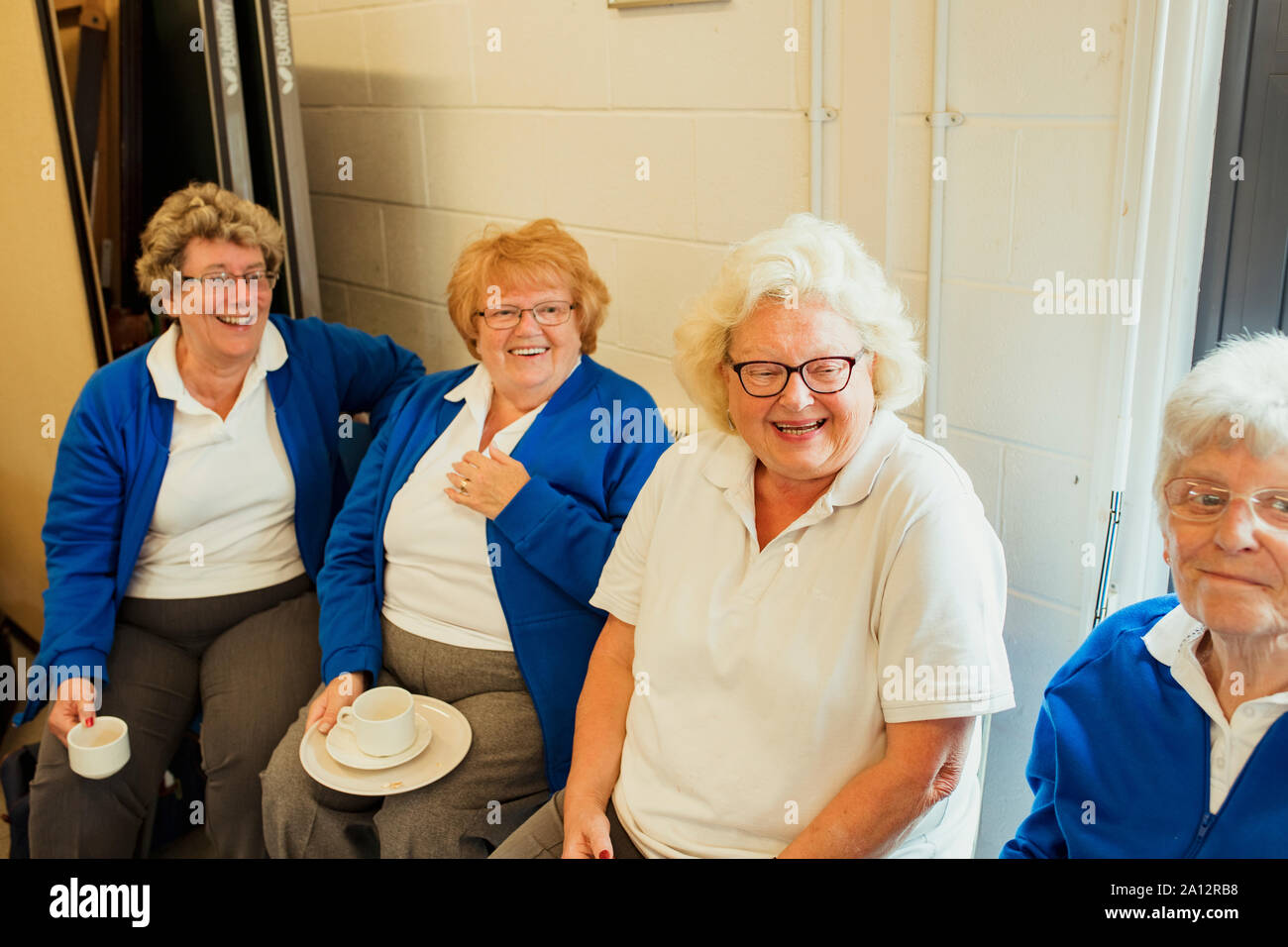 Vier älteren Frauen sitzen zusammen im Innenbereich und Kaffee. Sie lächeln und Verklebung mit einander. Stockfoto