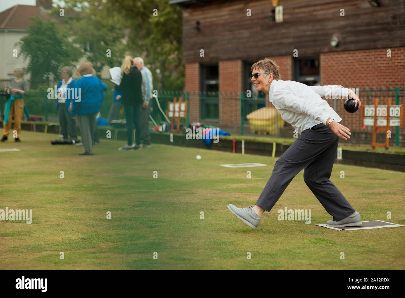 Eine Seitenansicht Schuss eine aufgeregte ältere Frau, die ihre Aufnahme in ein Spiel der Lawn Bowling. Stockfoto
